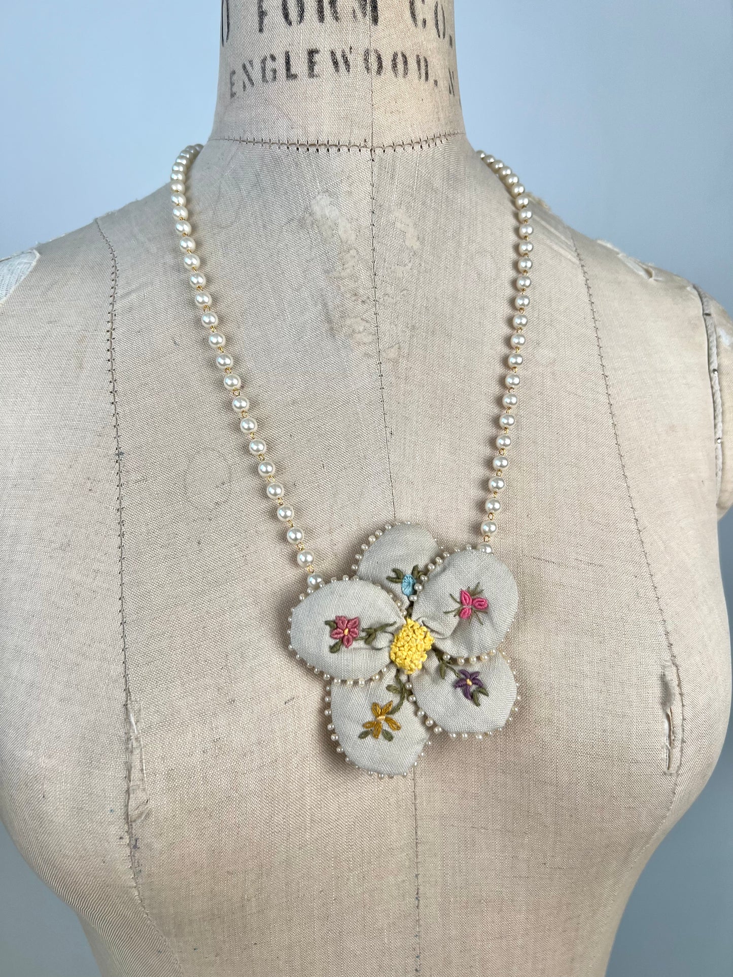 Collier de perles nacre à pendentif floral brodé